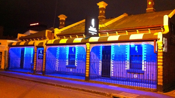 Blue-lit Collingwood Confidential brothel at night.